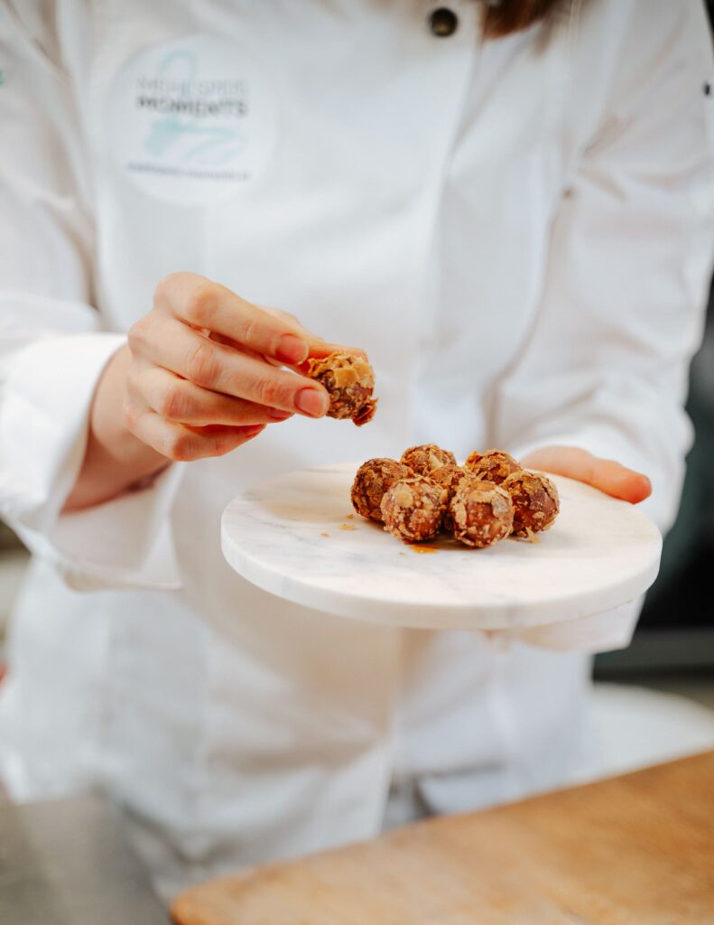 Ein Teller mit Apfelstrudel Pralinen wird in die Kamera gehalten auf einer Hand - in der anderen Hand hält die Person eine Praline