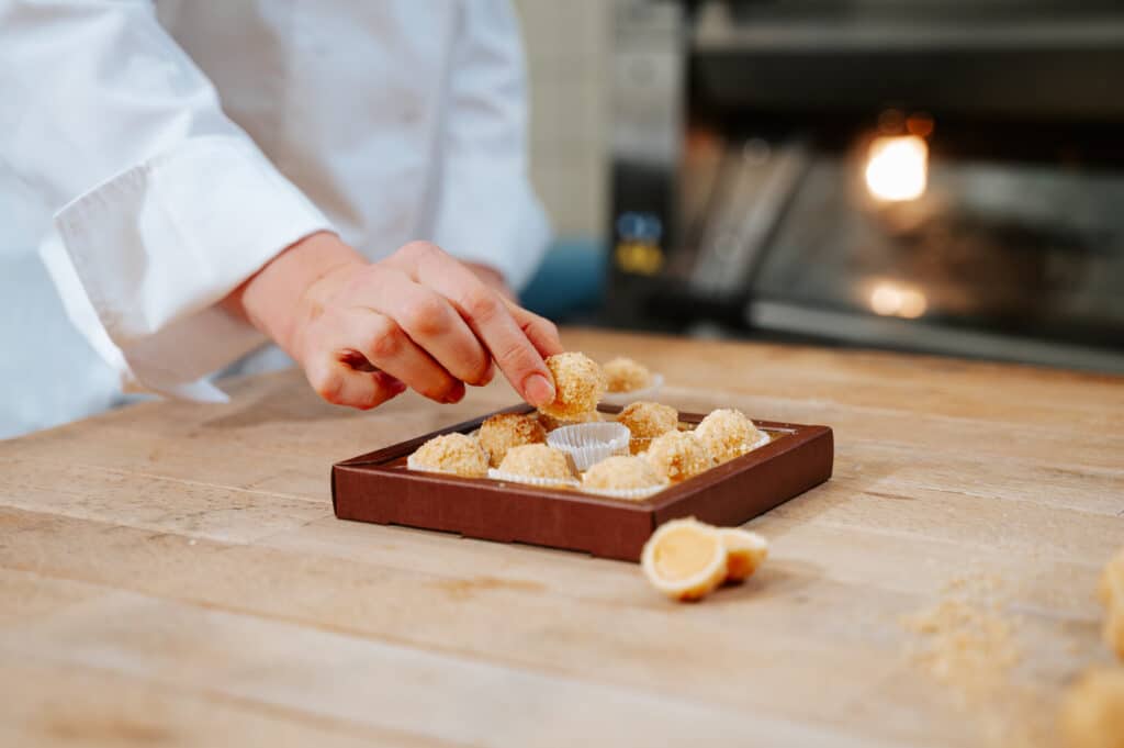 Geschenkpackung mit Marillenknödel Pralinen wo eine Hand hineingreift