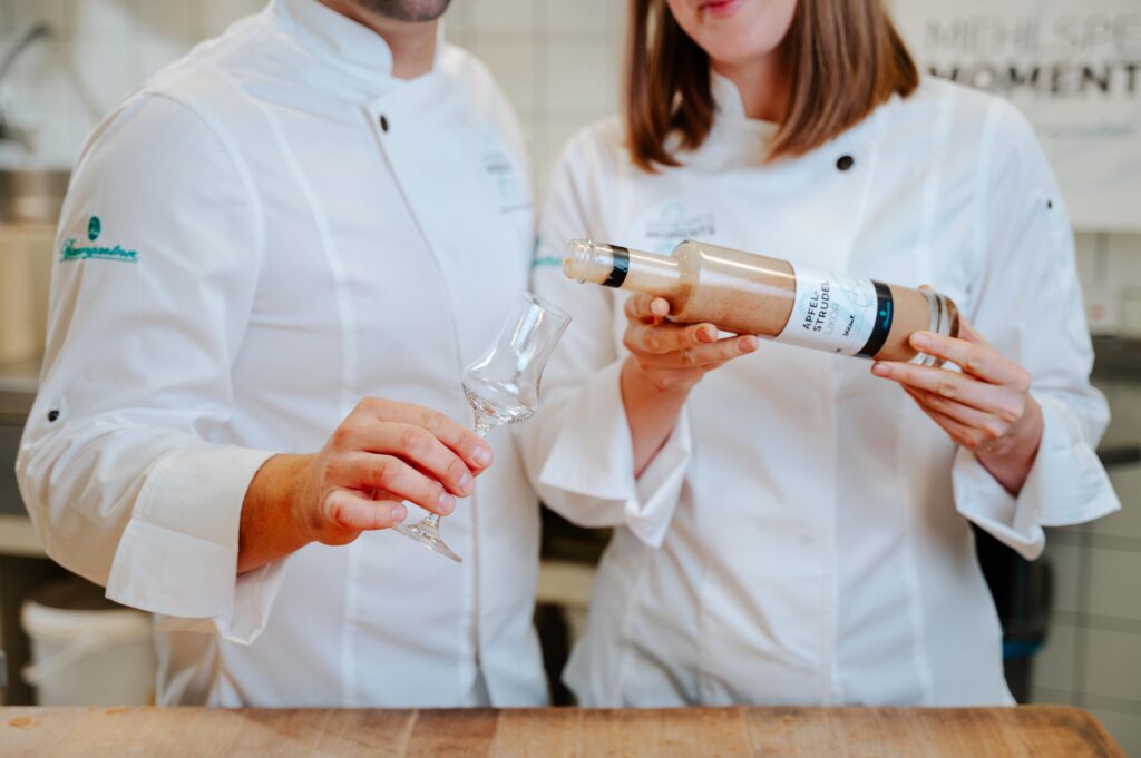 Nahaufnahme wie Julia und Mathias Baumgartner Apfelstrudel Likör in Glas einschenken