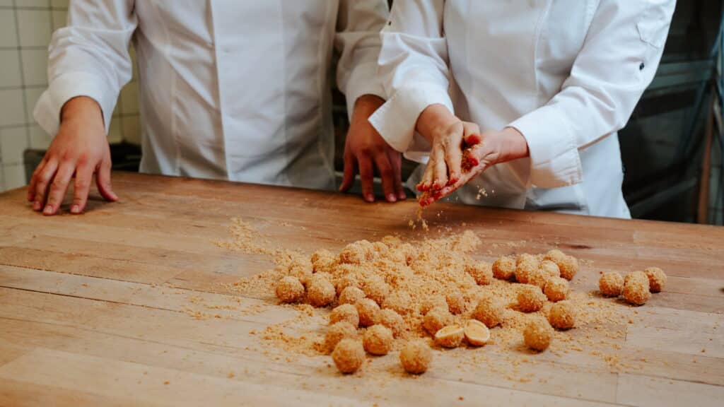 Marillenknödel Praline werden gerade in Butterbrösel gerollt