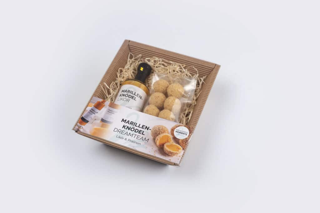 Marillenknödel Pralinen und Likör in einer Kartonverpackung mit Füllung von oben einsehbar mit dekorativer Banderole