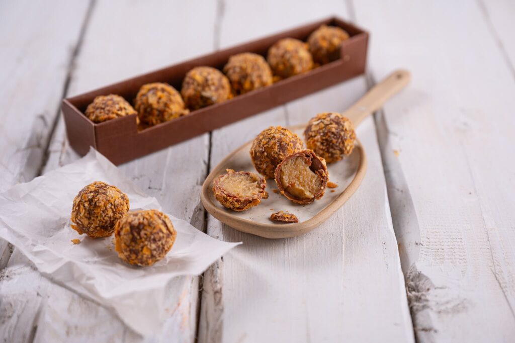 Apfelstrudel Praline schön präsentiert auf Holzlöffel, auf Backpapier und in der Geschenkpackung